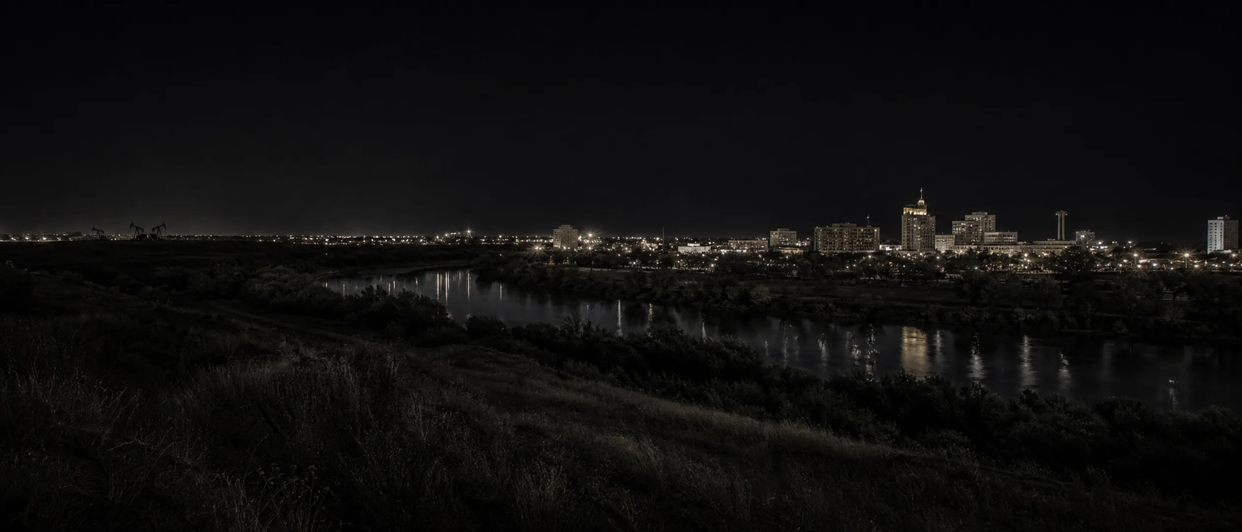 The Kern River and downtown Bakersfield seen from Panorama Bluffs at blue hour, with the Padre Hotel on the horizon.