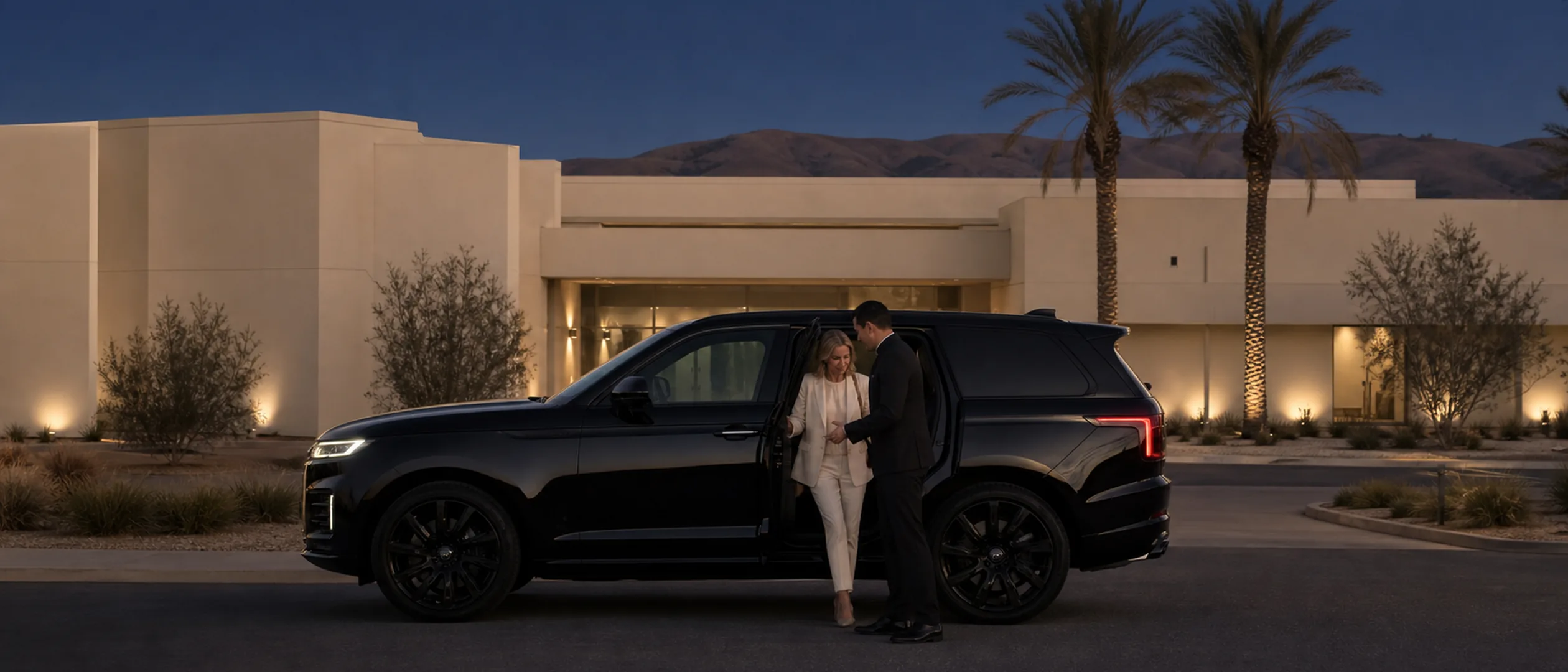 A passenger receives assistance beside a black SUV at a Bakersfield medical campus at dusk.