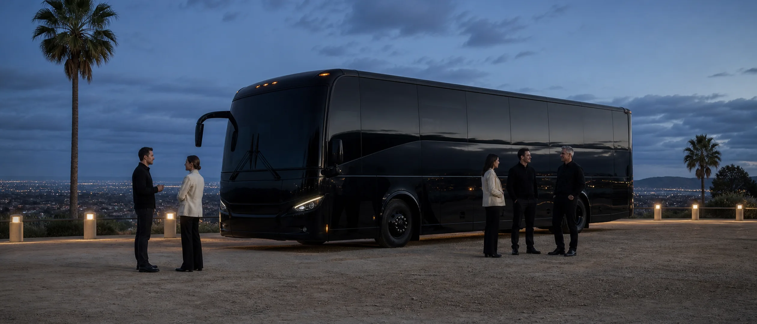 Travelers pause beside a black motorcoach at Bakersfield's Panorama Bluffs at dusk.